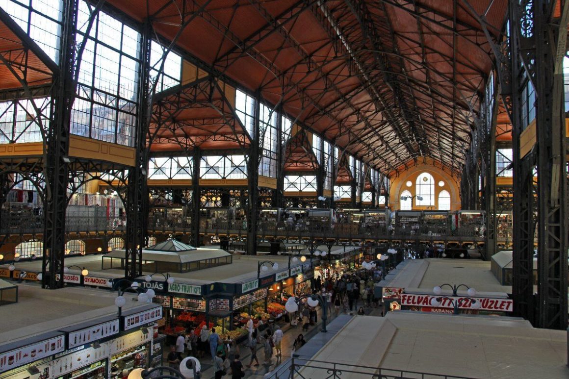 Vue intérieure du Grand Marché Central de Budapest, montrant la structure métallique Eiffel et les étals de produits locaux.