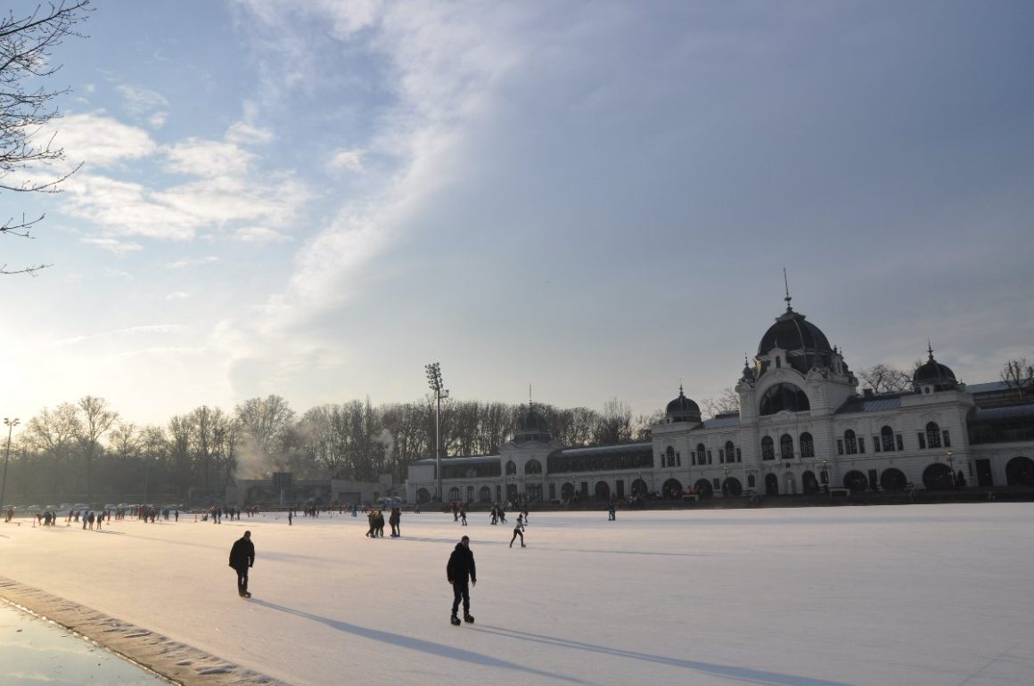 Patineurs sur la grande patinoire du parc Városliget en soirée.