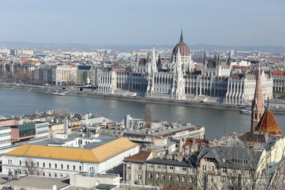Vue panoramique de Budapest depuis la colline, montrant la ville plate de Pest à gauche et le quartier du Château de Buda à droite, séparés par le Danube.