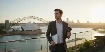 Jeune professionnel français travaillant sur un ordinateur portable avec la skyline de Melbourne en fond, illustrant le nouveau visa australie.