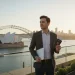 Jeune professionnel français travaillant sur un ordinateur portable avec la skyline de Melbourne en fond, illustrant le nouveau visa australie.