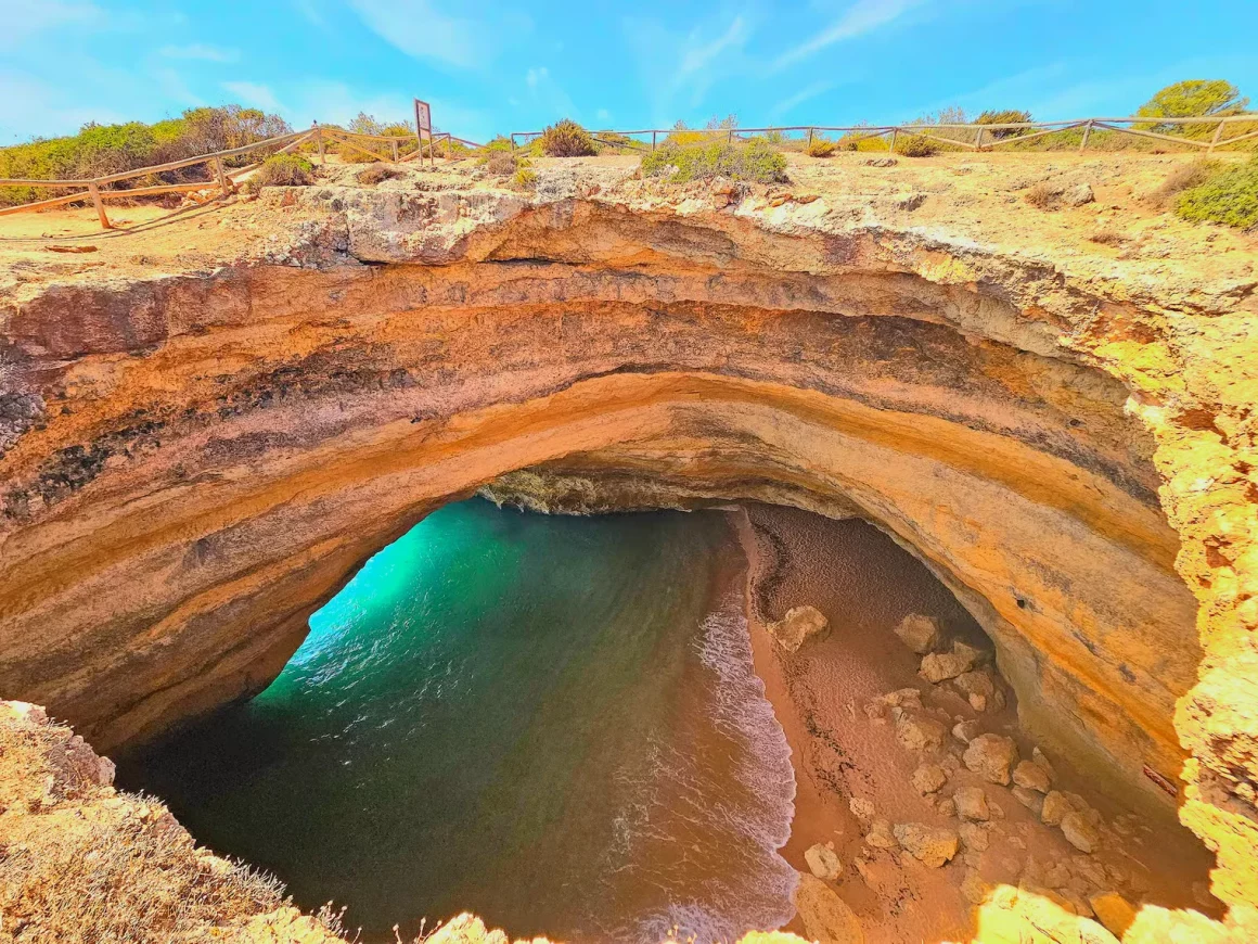 Vue plongeante sur la grotte de Benagil en Algarve depuis le sommet des falaises avec son ouverture naturelle dans le plafond
