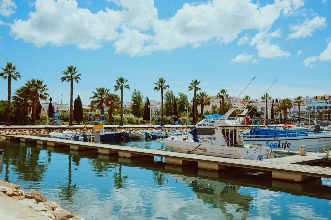 Marina de Faro au coucher du soleil avec bateaux de pêche et terrasses de restaurants face à la Ria Formosa