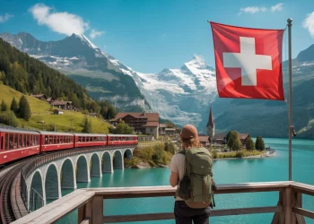 Train panoramique traversant les Alpes suisses avec vue sur les montagnes et un lac turquoise