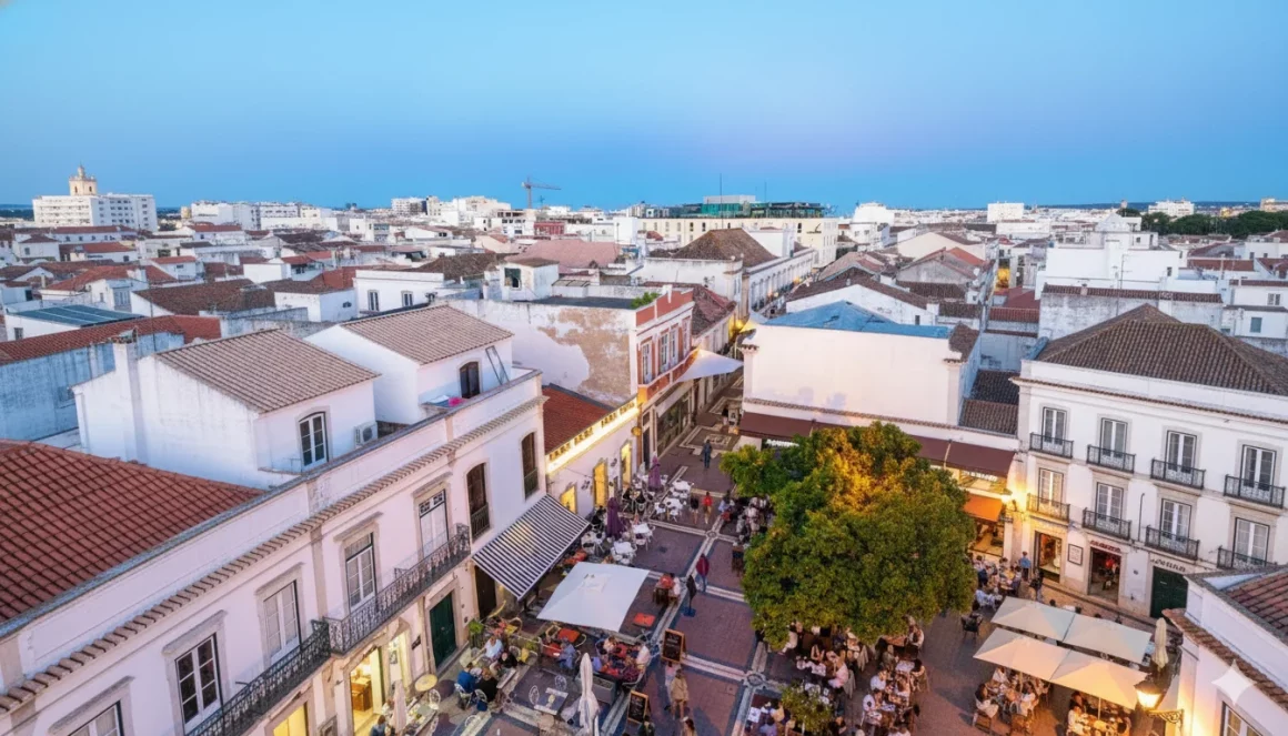 Rue piétonne du centre historique de Faro avec façades typiques portugaises et terrasses de cafés